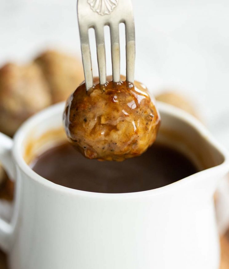 stuffing ball being dunked into small pot of gravy