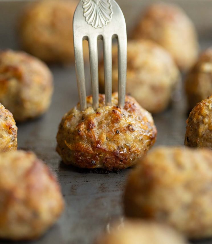 close up shot of fork digging into stuffing ball on oven tray