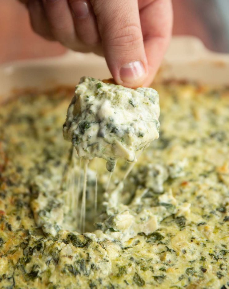 Ritz cracker scooping out dip out of dish with cheese pull