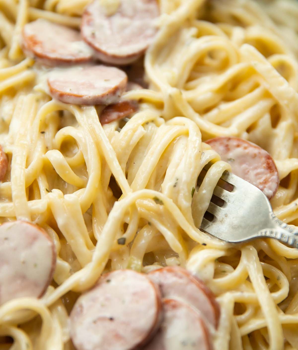 closeup shot of silver fork digging into skillet of pasta