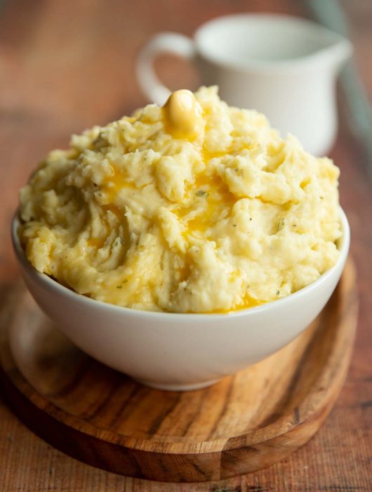 mashed potatoes served in small white bowl with jug blurred in background