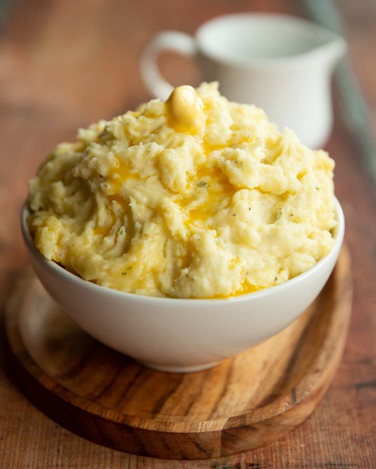 mashed potatoes served in small white bowl with jug blurred in background