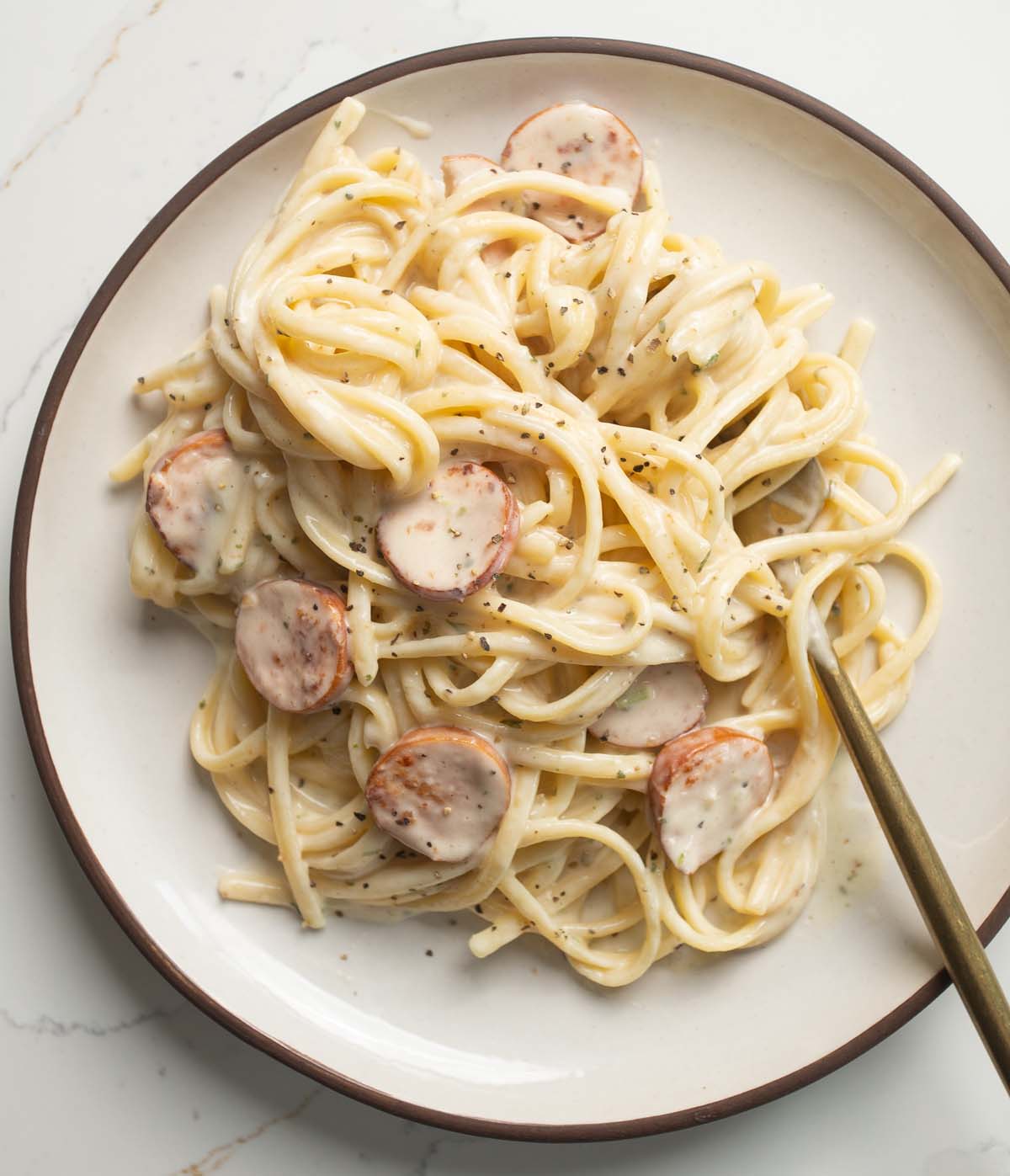 overheas shot of boursin pasta on small white plate with golden fork