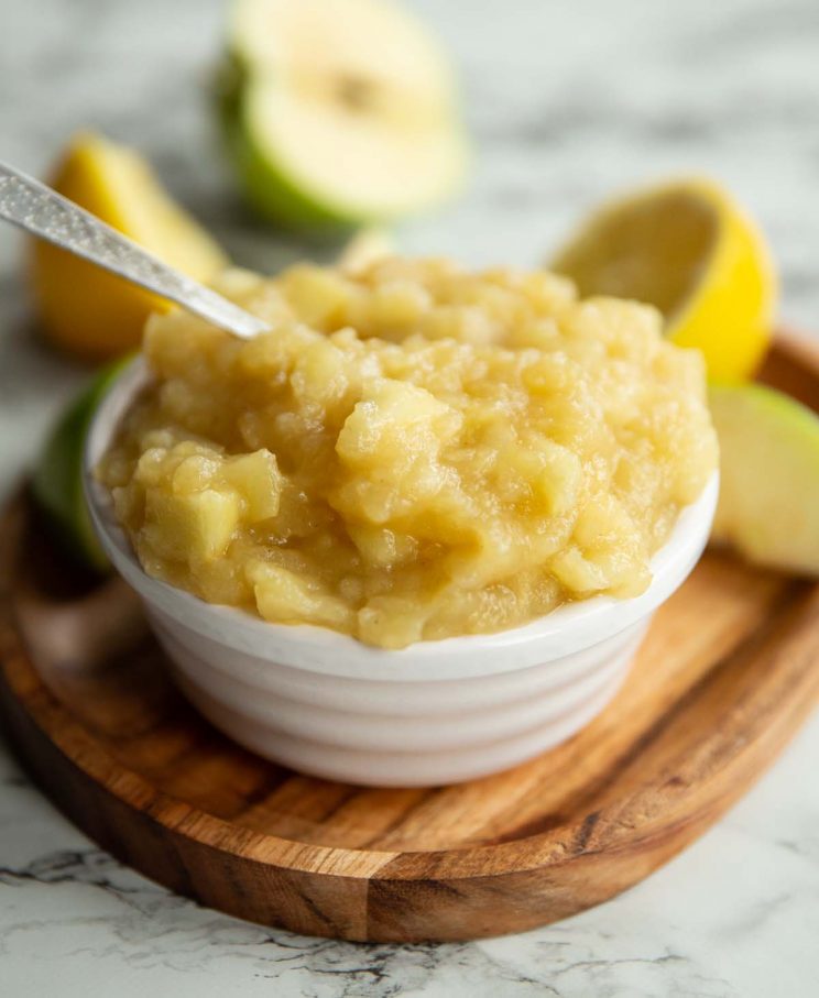 apple sauce in small white pot surround by apples and lemon