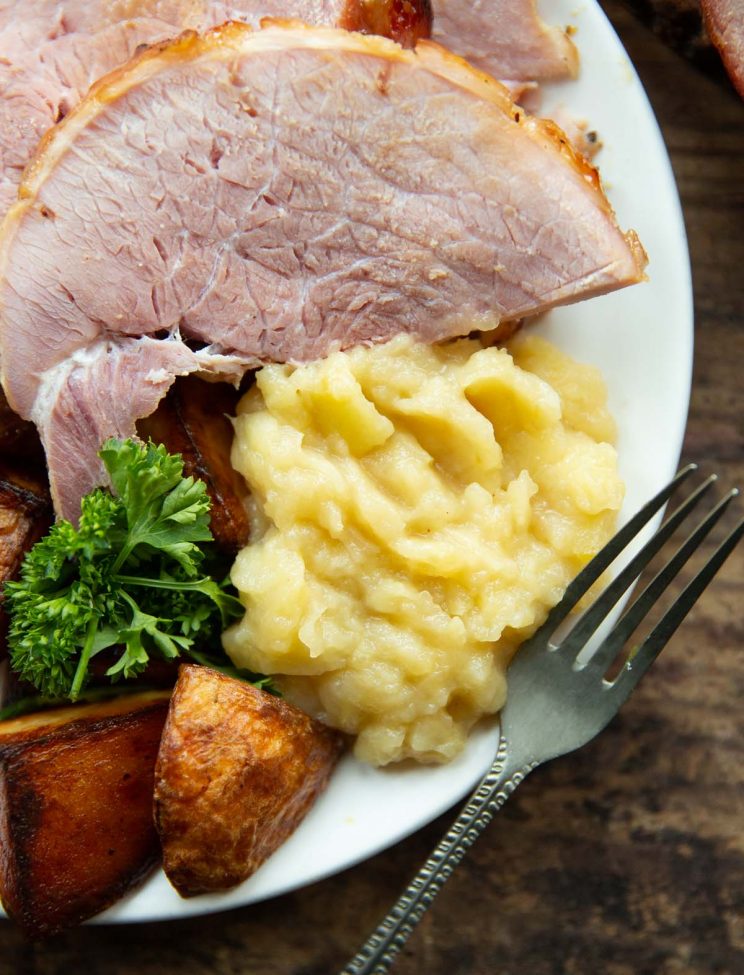 overhead shot of apple sauce on plate with ham and roast potatoes