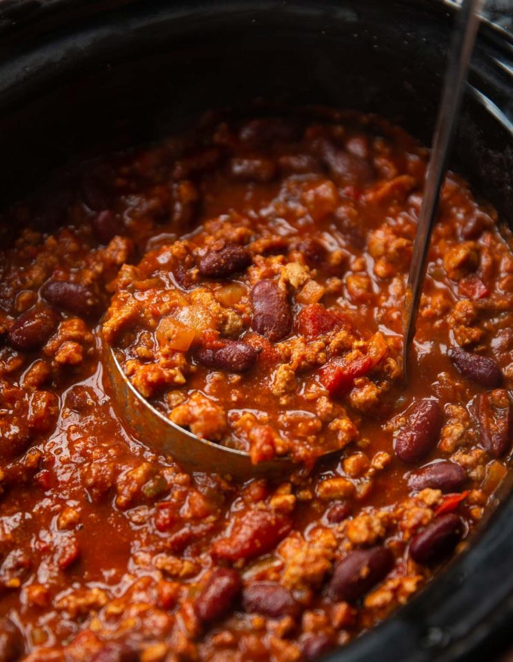 close up shot of ladle in slow cooker scooping out chili