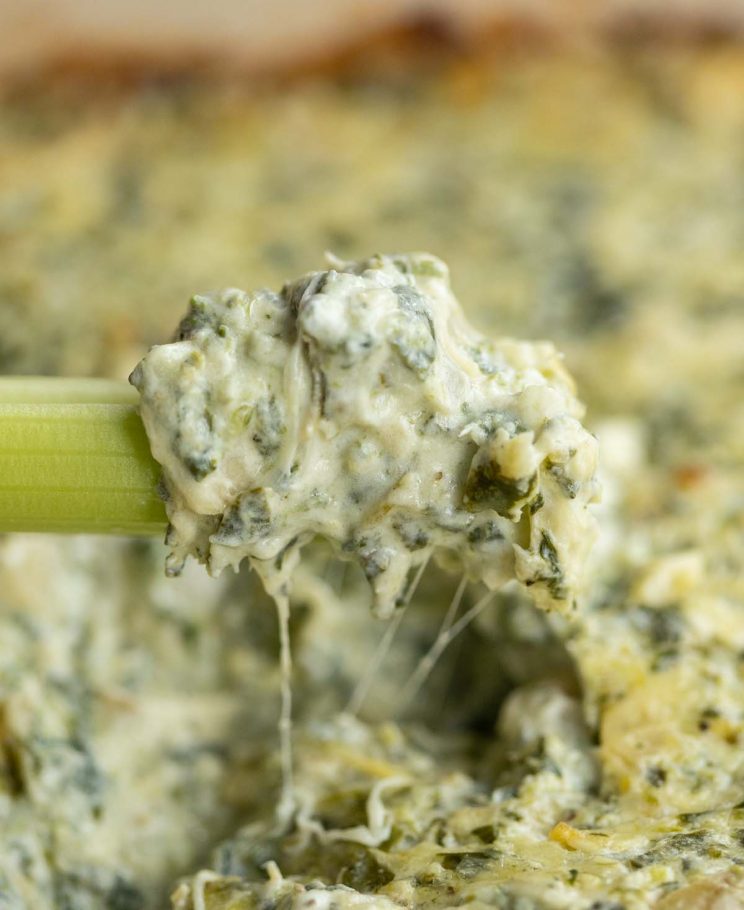 celery scooping out dip from baking dish