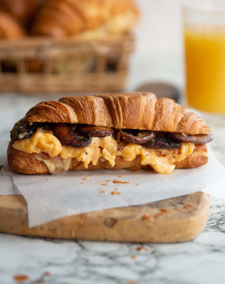 croissant on wooden board with juice and croissants blurred in background