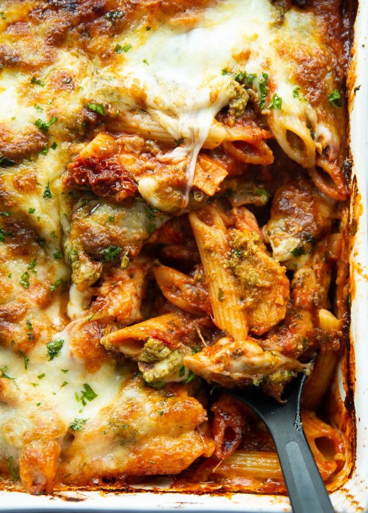 overhead shot of serving spoon digging into pasta bake in serving dish