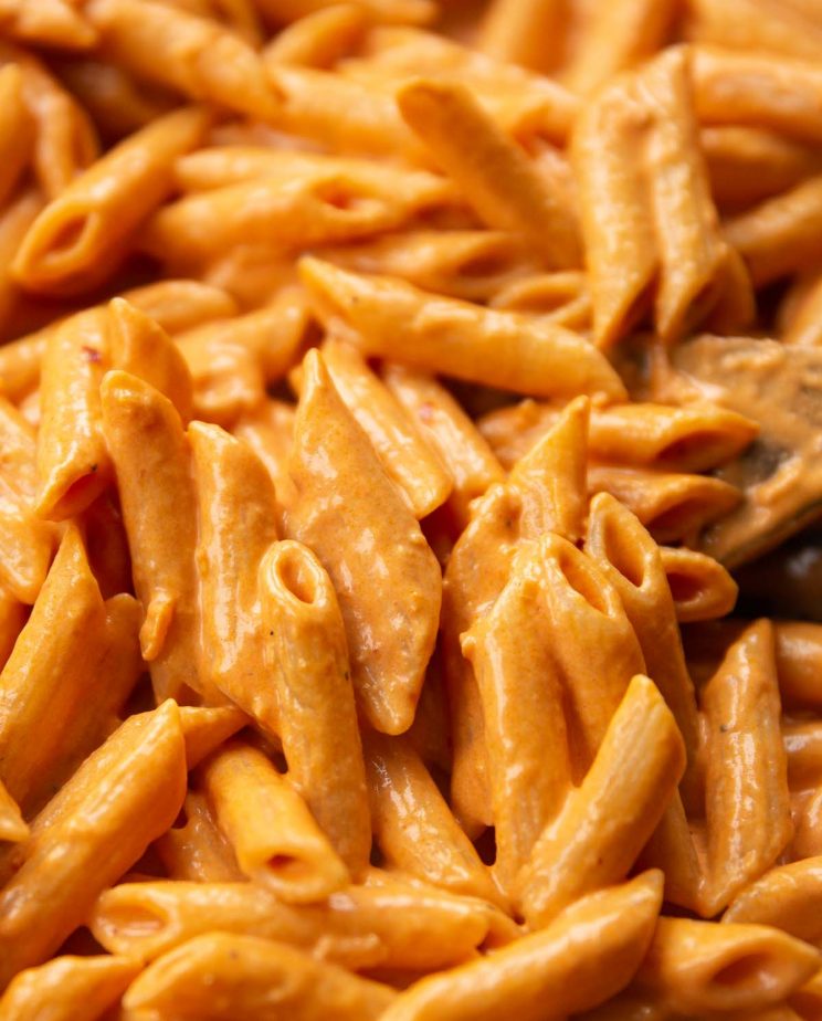 close up shot of pasta in skillet with wooden spoon digging in