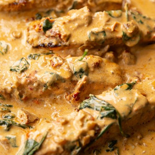 close up shot of 4 salmon fillet sin creamy cajun sauce in skillet