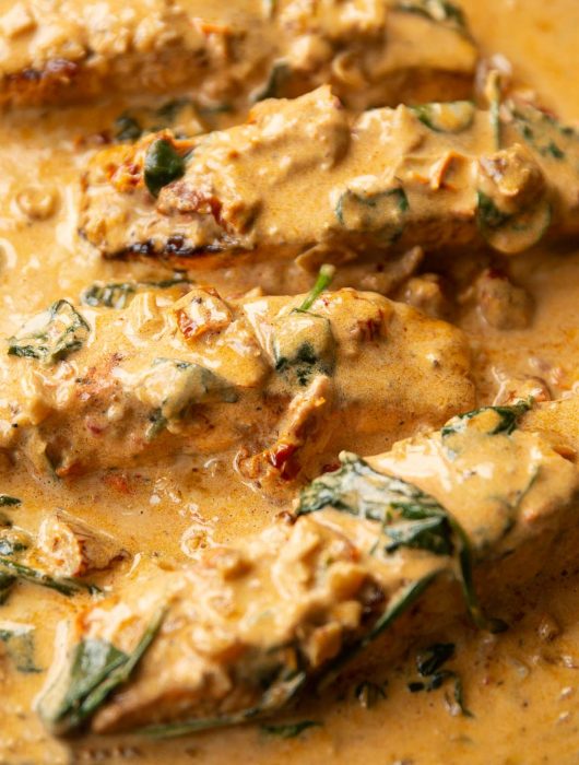 close up shot of 4 salmon fillet sin creamy cajun sauce in skillet