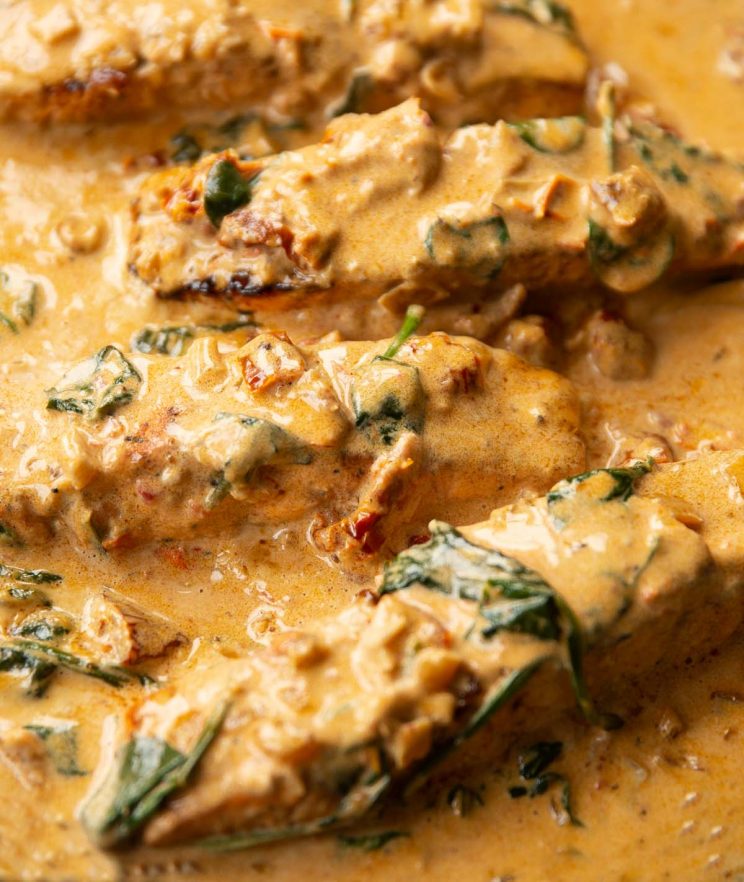 close up shot of 4 salmon fillet sin creamy cajun sauce in skillet