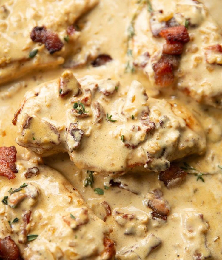 close up shot of bacon chicken in skillet garnished with thyme