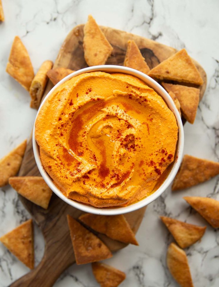 overhead shot of dip served in small white bowl surrounded by pita chips