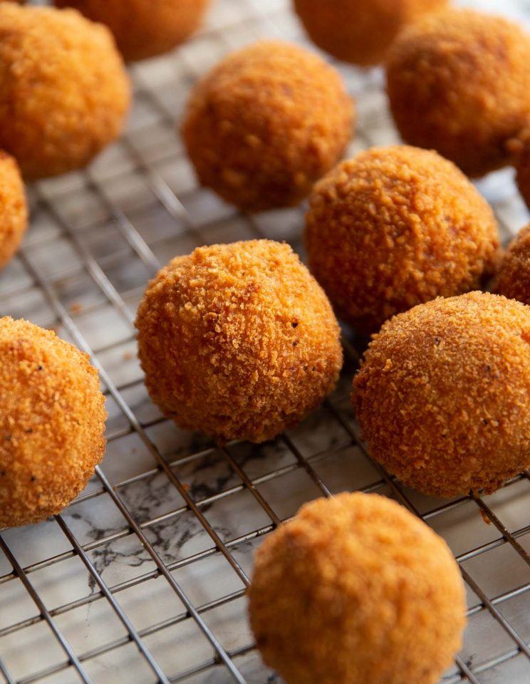 close up shot of mini kievs on wire rack on marble back drop