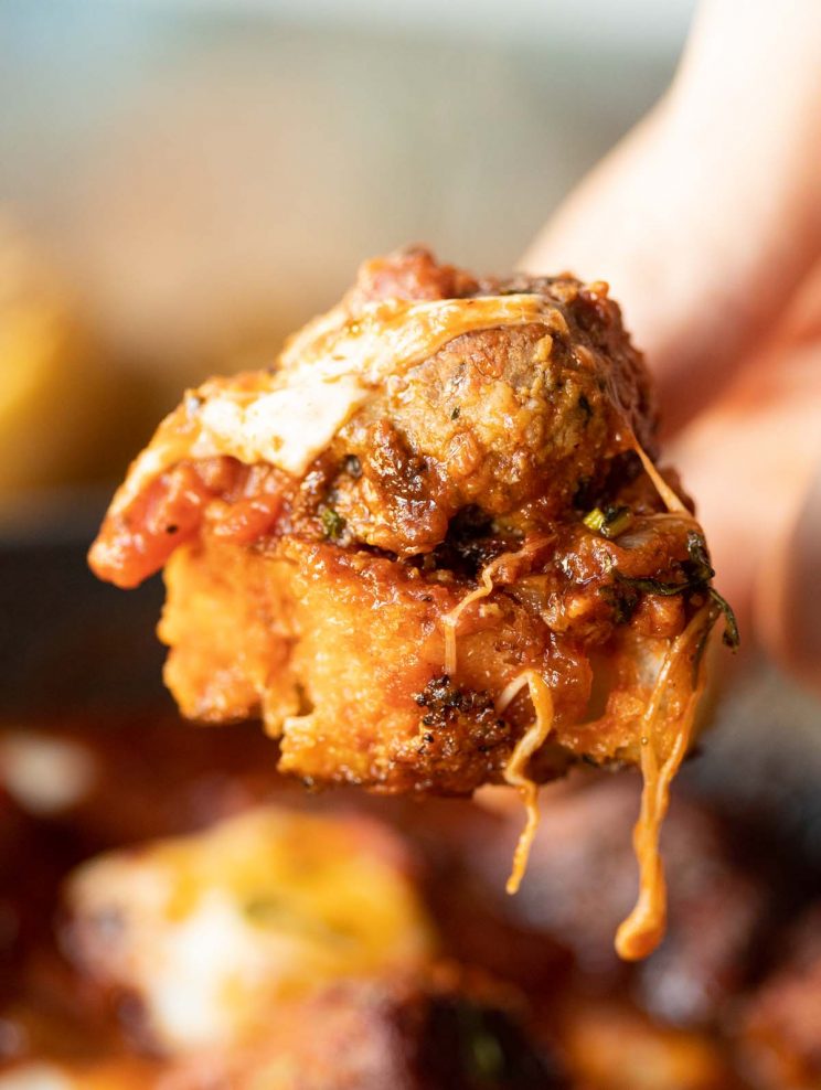 close up shot of meatball on bitten piece of garlic bread