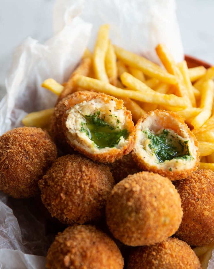 close up shot of kiev spli ton half on top of more kievs and french fries
