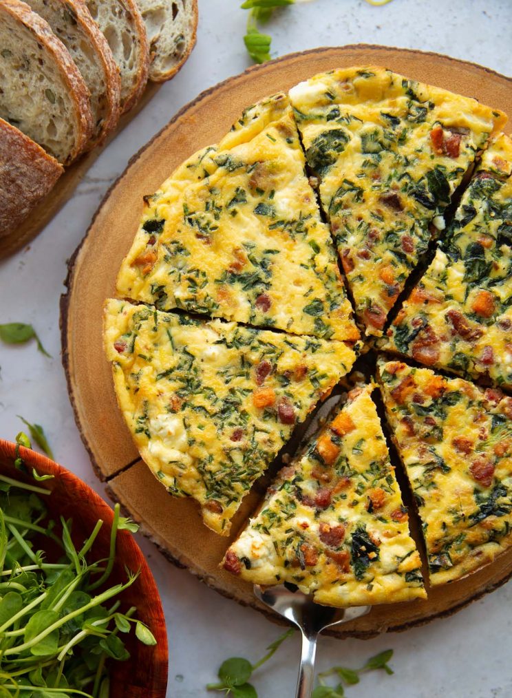 overhead shot of frittata on wooden board sliced into 6