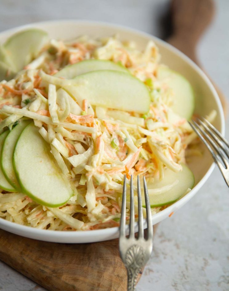 apple slaw in big white bowl with two silver forks resting on it