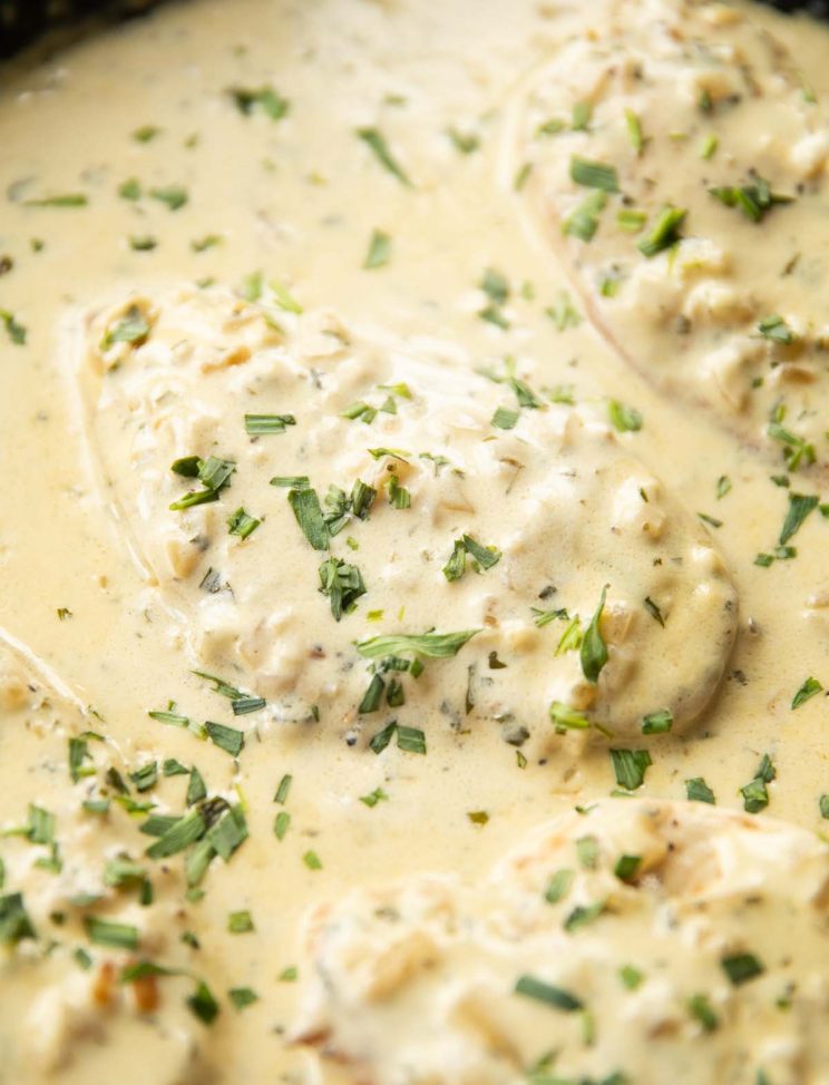 close up shot of chicken in pan garnished with tarragon
