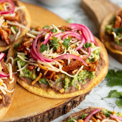 tostada on wooden board surrounded by garnish and more tostadas