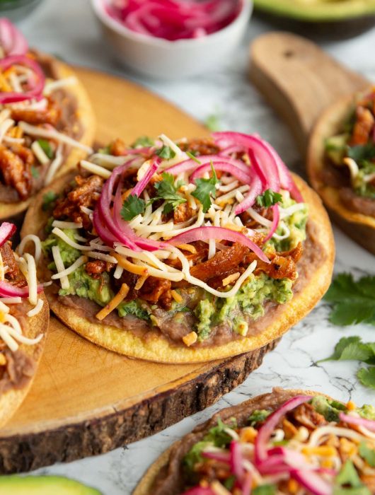 tostada on wooden board surrounded by garnish and more tostadas