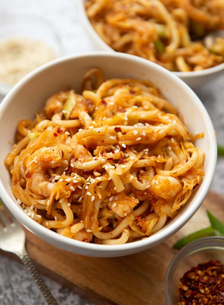 closeup shot of noodles in small white bowl on wooden chopping board with second bowl blurred in background