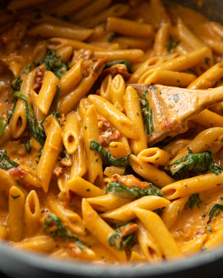 close up shot of wooden spoon digging into pot of pasta