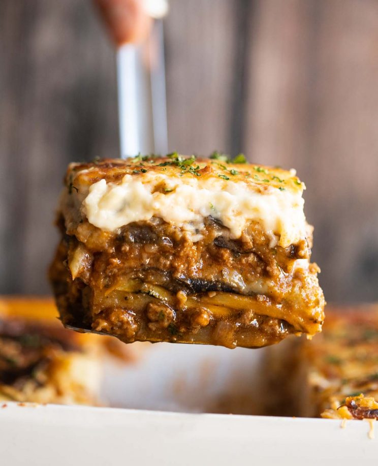 close up shot of metal spatula scooping moussaka out of dish