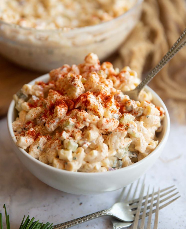 pasta salad served in a small white bowl with silver fork digging in