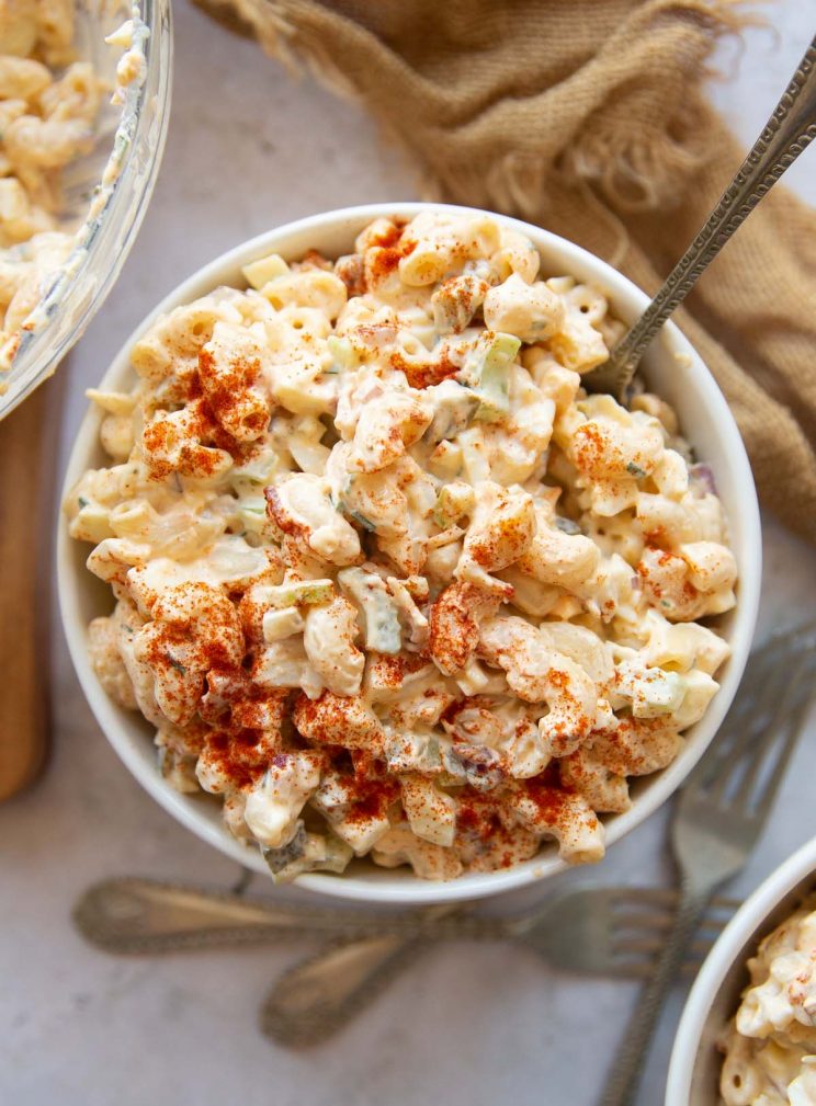 overhead shot of pasta salad in small white bowl with silver fork digging in