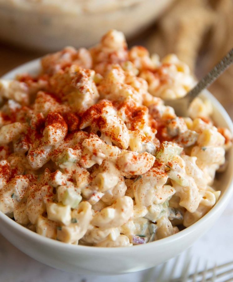 closeup shot of pasta salad served in small white bowl with fork digging in