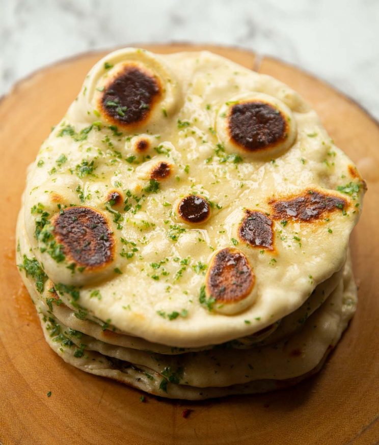 4 garlic flatbreads stacked on each other on wooden board