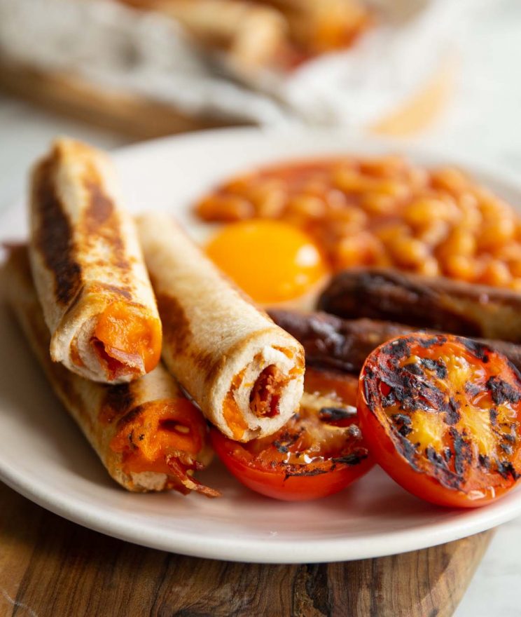 3 grilled cheese roll ups served on small white plate with breakfast items