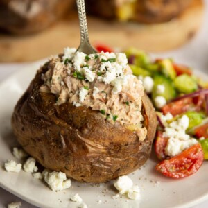 tuna baked potato on white plate with silver fork digging in next to side salad