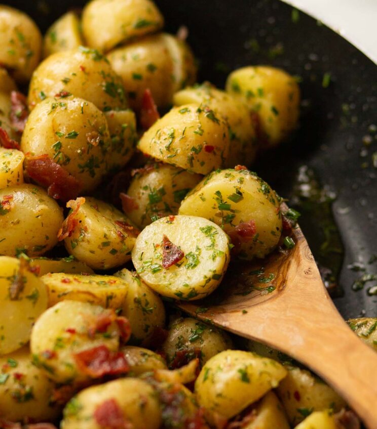 close up shot of wooden spoon digging into potato salad in frying pan