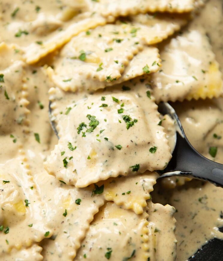 close up shot of ravioli in pan with black serving spoon digging in