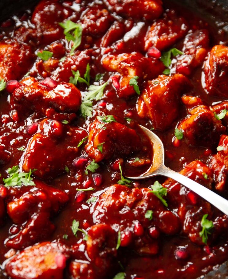 close up shot of spoon digging into pomegranate chicken in skillet
