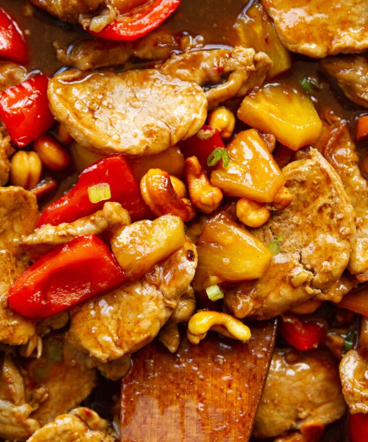 close up overhead shot of pork and pineapple with wooden spoon digging in