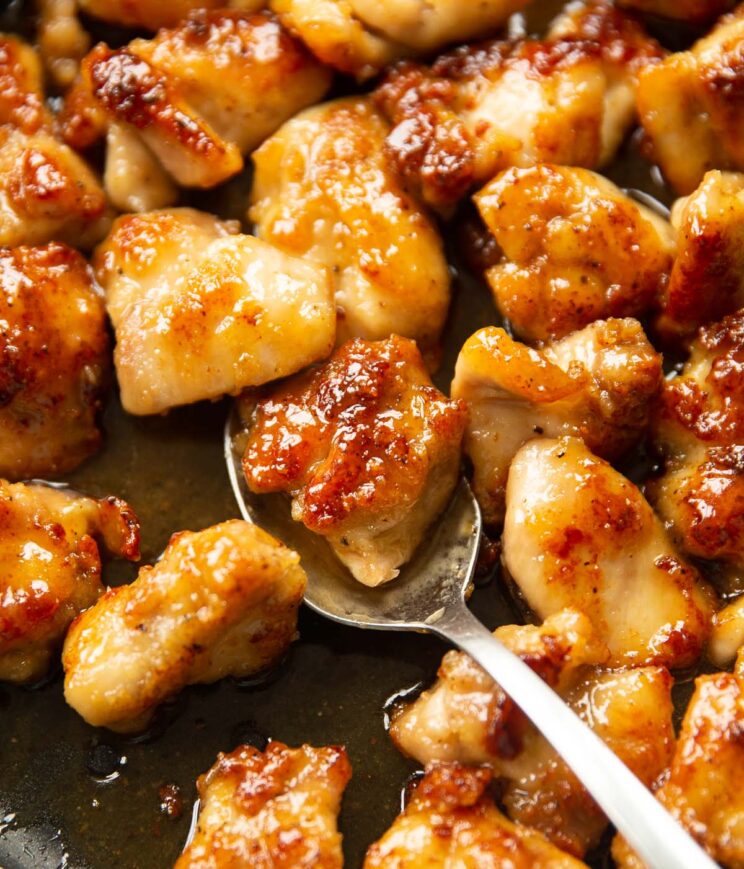 close up shot of silver spoon digging into pan of honey butter chicken