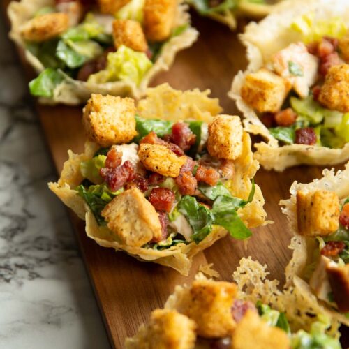 caesar salad parmesan cups on long dark wooden board