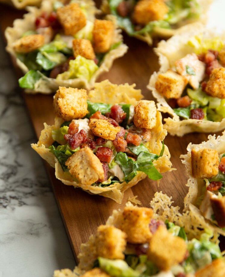 caesar salad parmesan cups on long dark wooden board