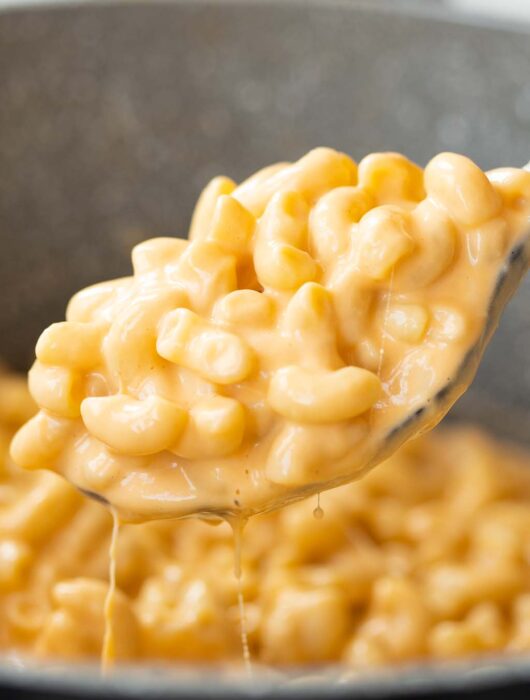 close up shot of mac and cheese on serving spoon scooping out of pot