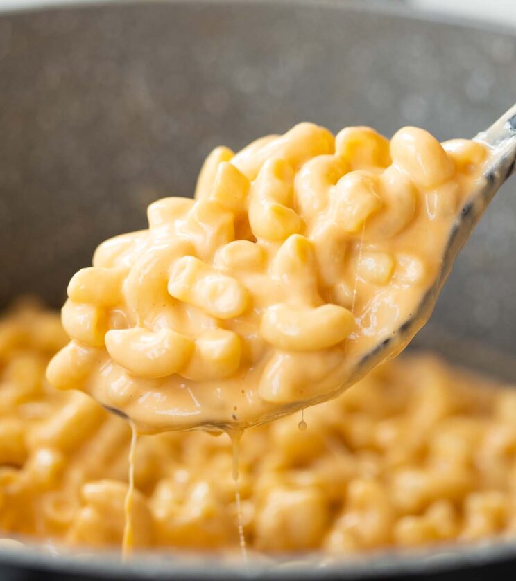 close up shot of mac and cheese on serving spoon scooping out of pot