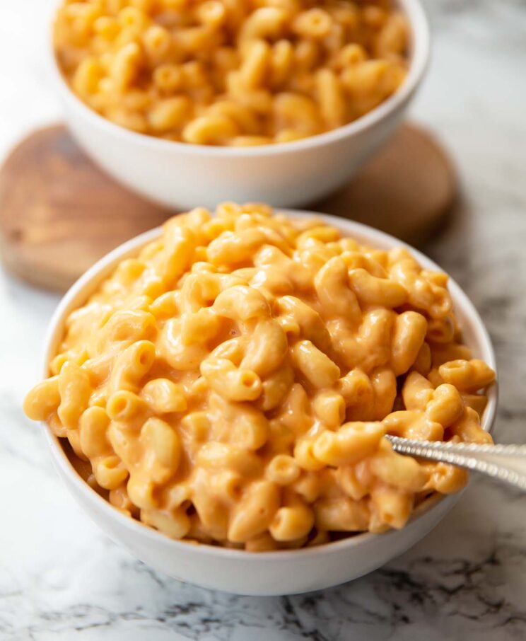 two small white bowls of mac and cheese on marble backdrop