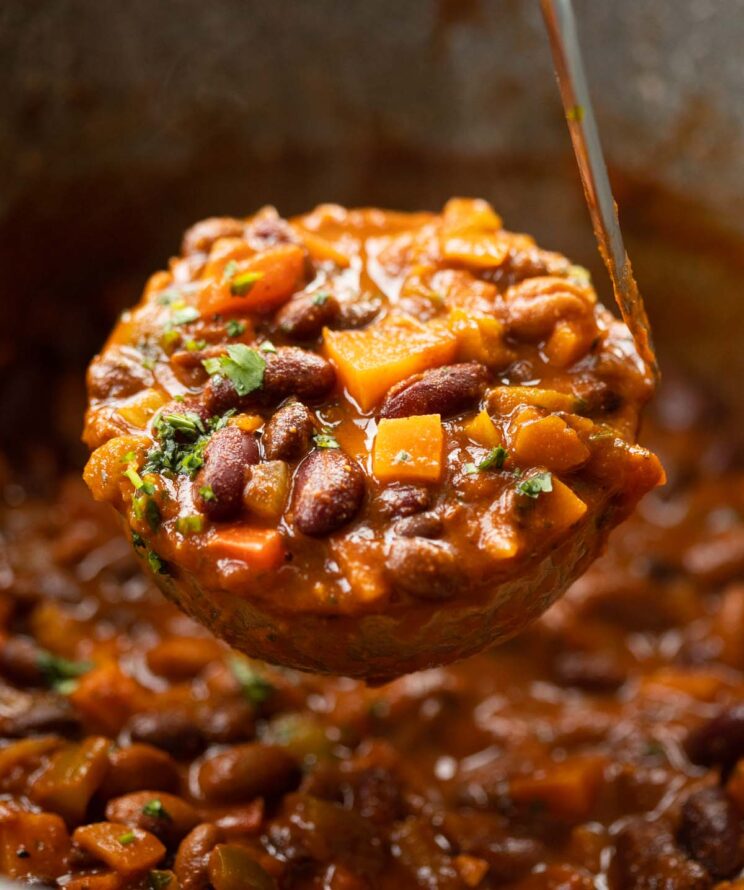 close up shot of ladle scooping out 3 bean chilli from large pot
