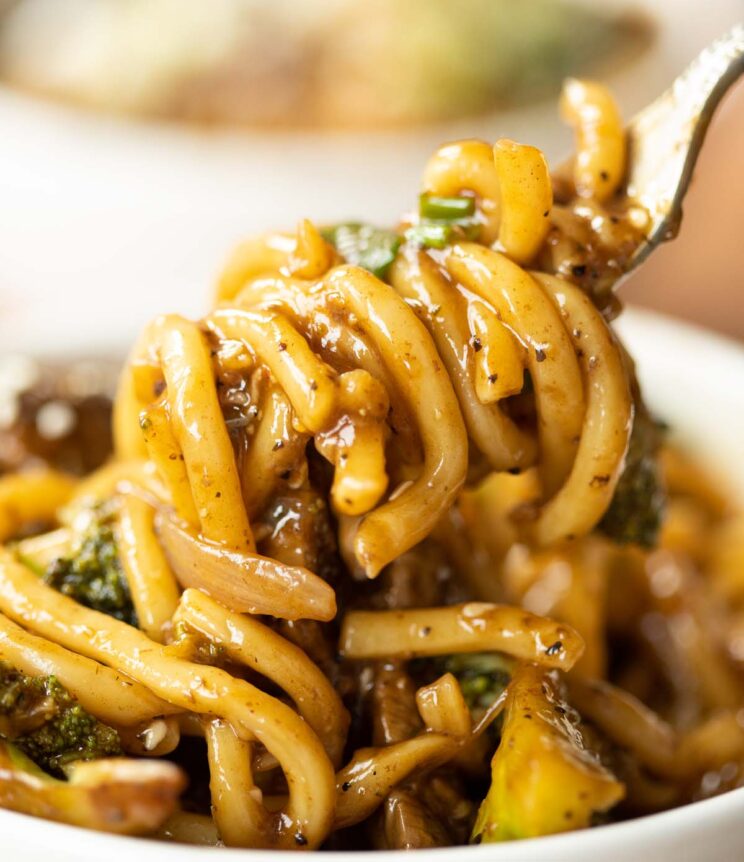close up shot of silver fork twizzling noodles in small white bowl