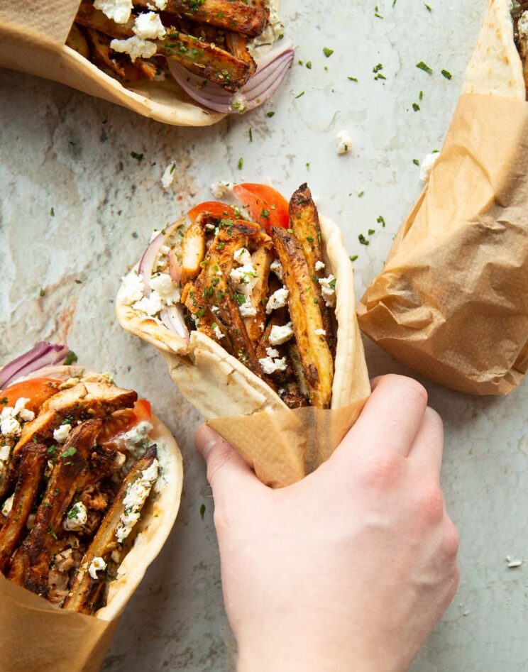 overhead shot of hand grabbing chicken gyros with 3 others in photo