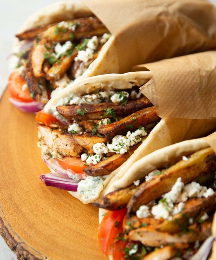 close up shot of 3 Greek chicken gyros on wooden board